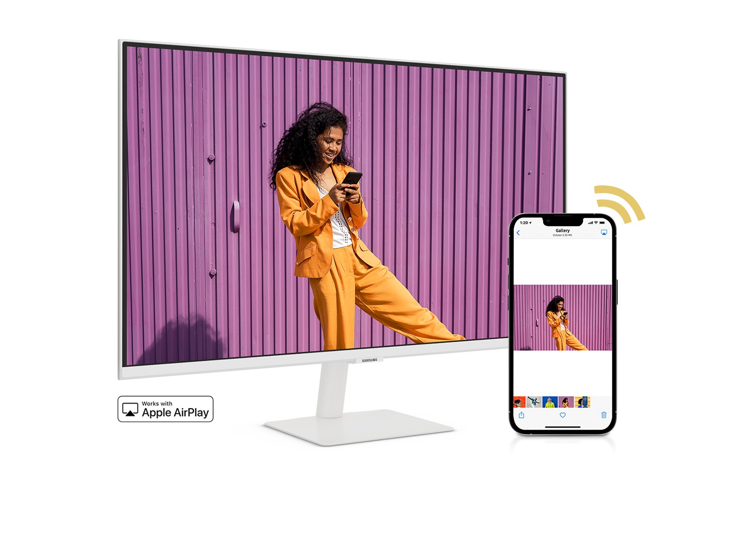 A smartphone and monitor sit side-by-side. The smartphone shows a woman posing with a skateboard. The same woman with skateboard is shown on the monitor. The smartphone's gallery app swipes through different photos which are also shown on the monitor screen.