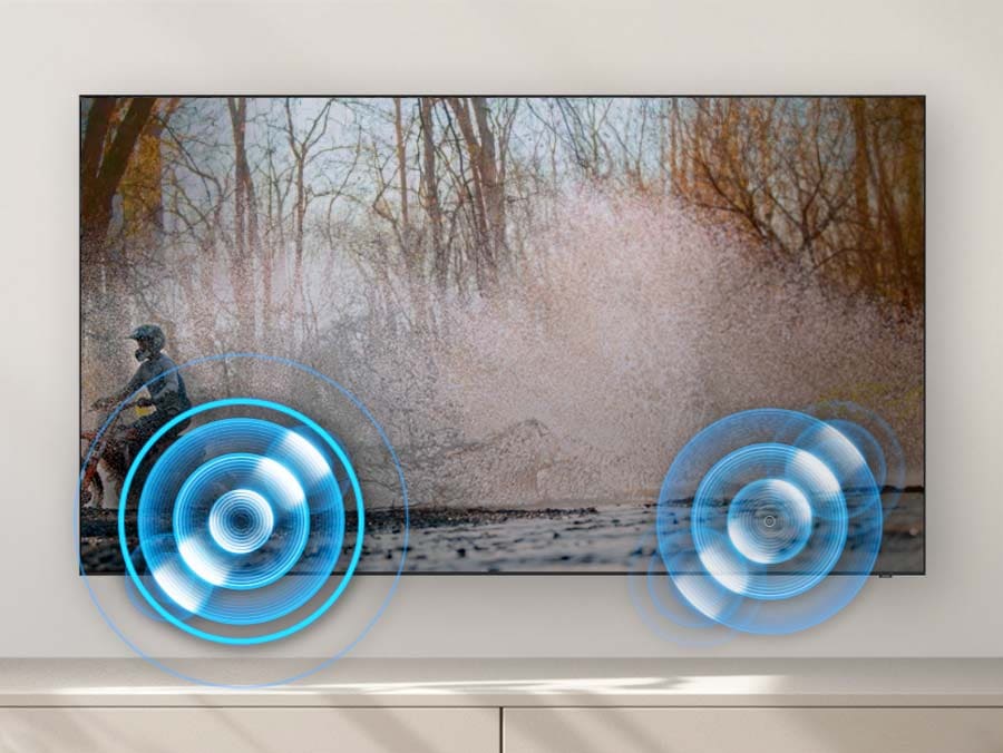A person on a motorcycle is zipping past from one side to another on a Samsung QA55Q60CAUXZN TV screen. Built-in speakers follow the sound of the motorcycle as it moves.