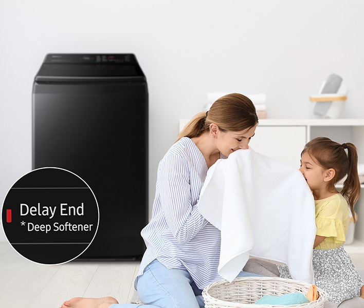 Side of the washing machine,a woman is smelling a towel with her daughter. The towel was washed using the Deep Softenter of the Delay End course.