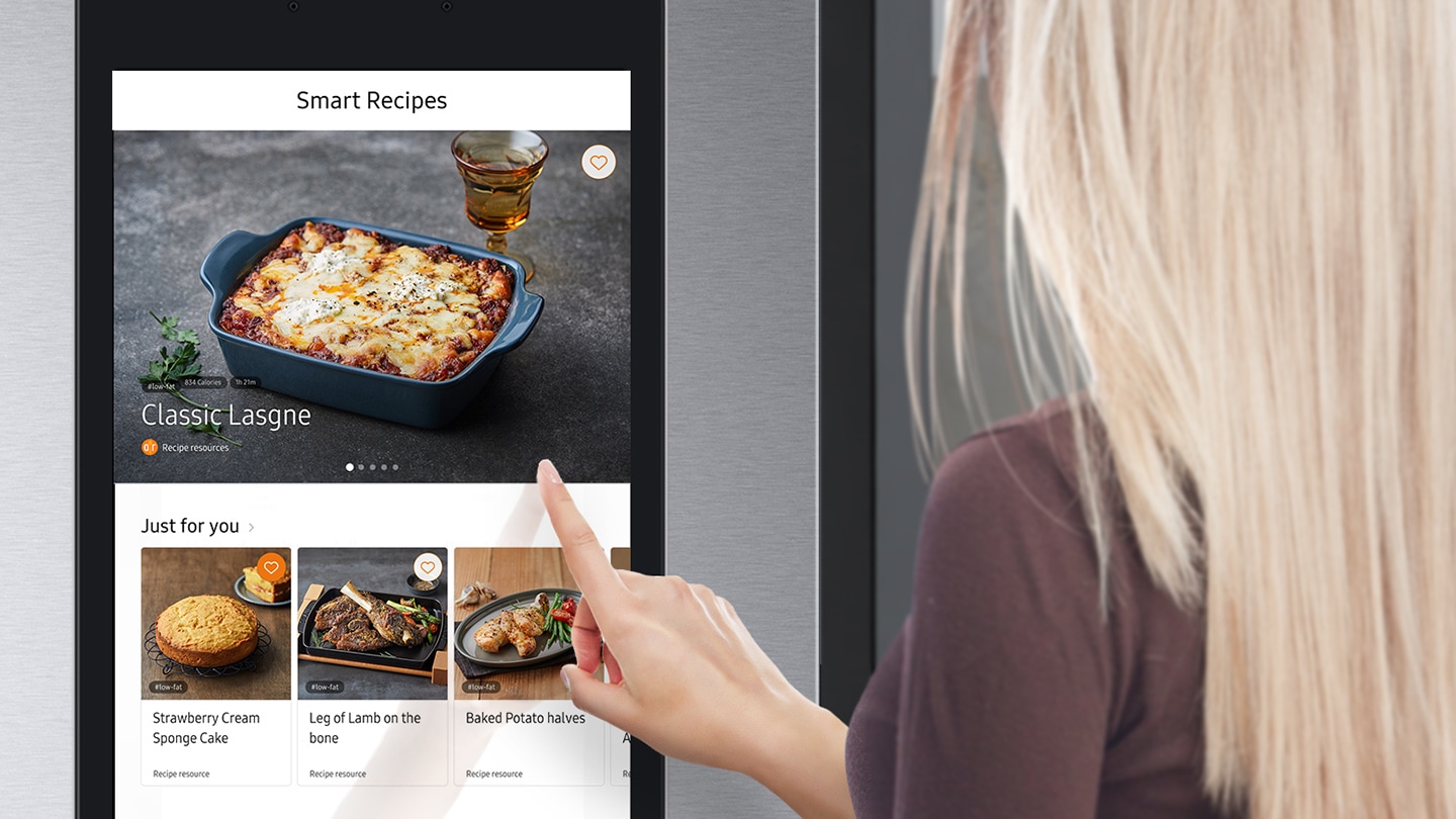 The woman is checking the recipes for the food with the Smart Recipes app on the Family Hub screen.