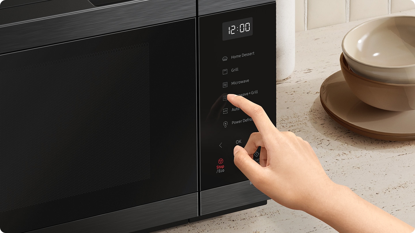 A person is touching the control panel of the microwave.