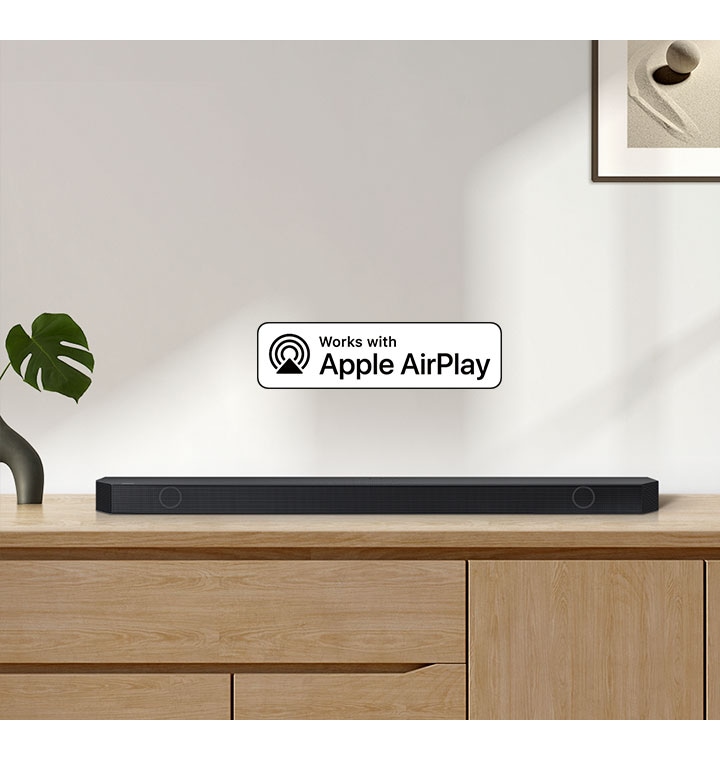 A Samsung Soundbar sits on top of a cabinet, accompanied by a logo for Works with Apple AirPlay.