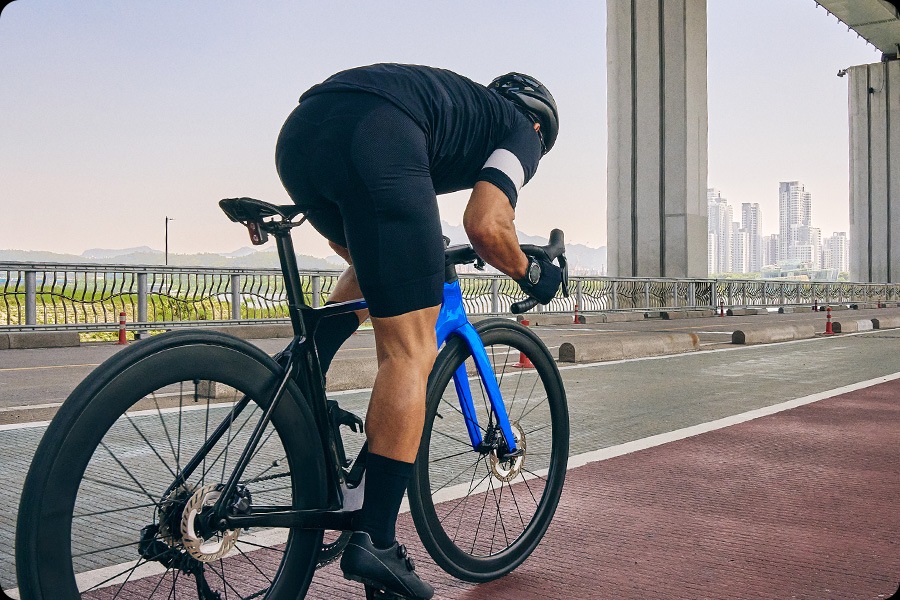 A man in cycling gear is riding a road race bike along a bike path.