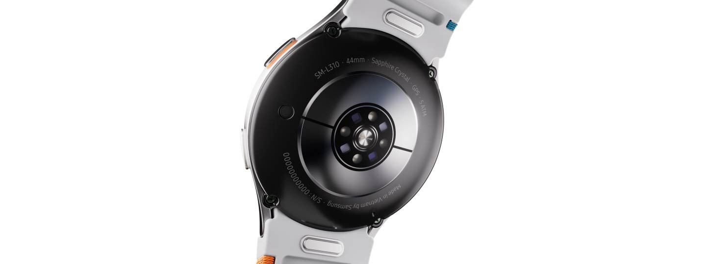 A Galaxy Watch7 seen from the back showing its Electrical Bio-signal Sensor and Optical Bio-signal Sensor with green LED light emitting from the center.