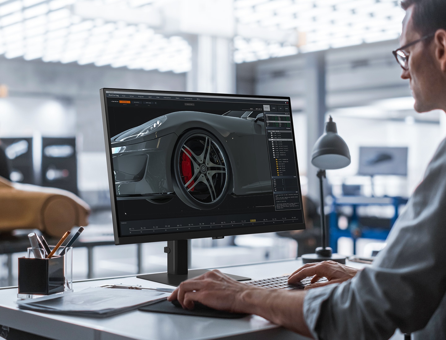 A man sits at a desk with a car in the background. He's editing an image of a car on his screen. Above the monitor reads "Expand your creative realm."