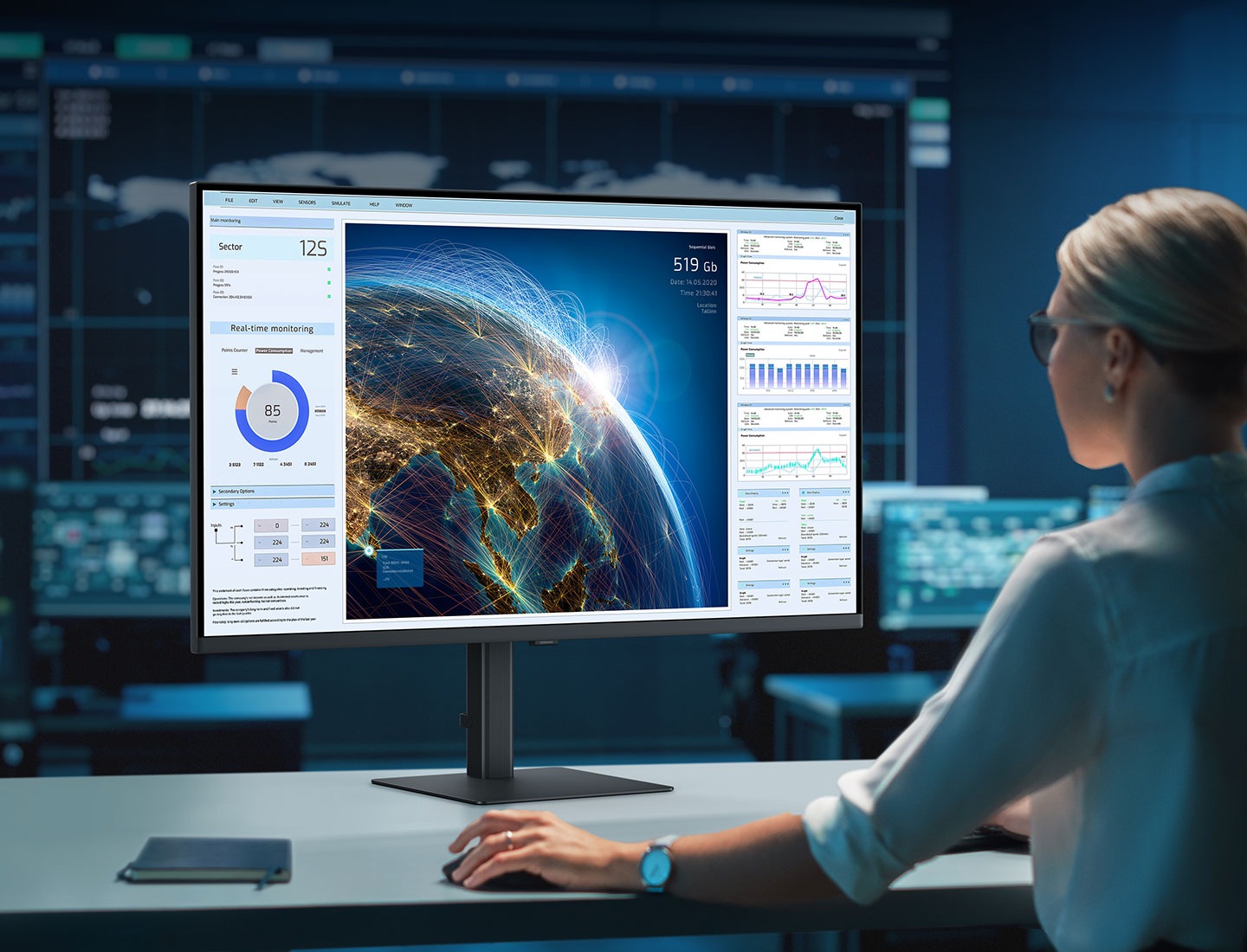 A man sits at a desk in front of a server rack. He is using two monitors. The left monitor is horizontal, showing a world map. The right monitor is vertical, showing numerous graphs and charts. Above the monitor reads "Expand your creative realm."
