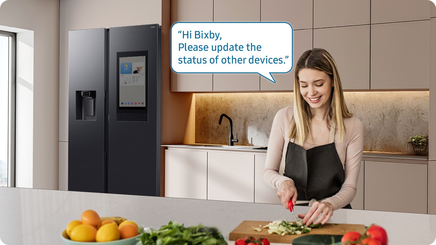 Shows a person preparing food while controlling the refrigerator using a Samsung Bixby. “Hi Bixby, Please update the status of other devices.”