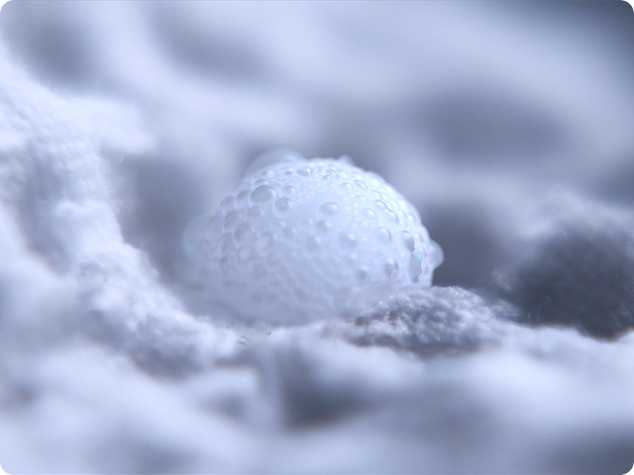 An ultra close-up of a bubble with dirt on the fabric of a piece of clothing, indicating AI bubble's efficient wash. 