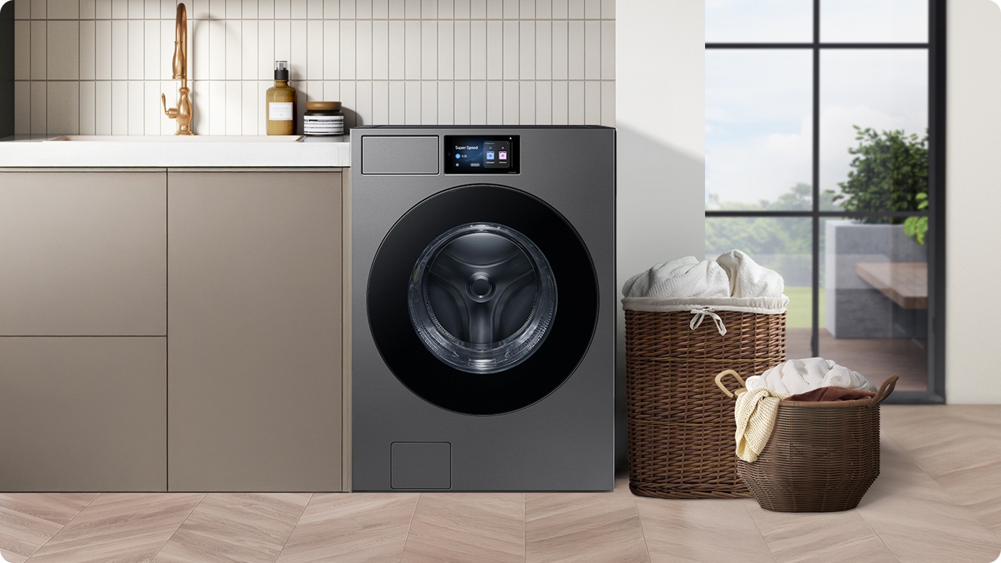 A washer is installed in a modern utility room, next to a sink with two full laundry baskets nearby.
