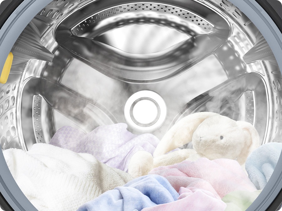 A close-up of towels, clothes, and a bunny doll inside the washer drum, surrounded by steam.