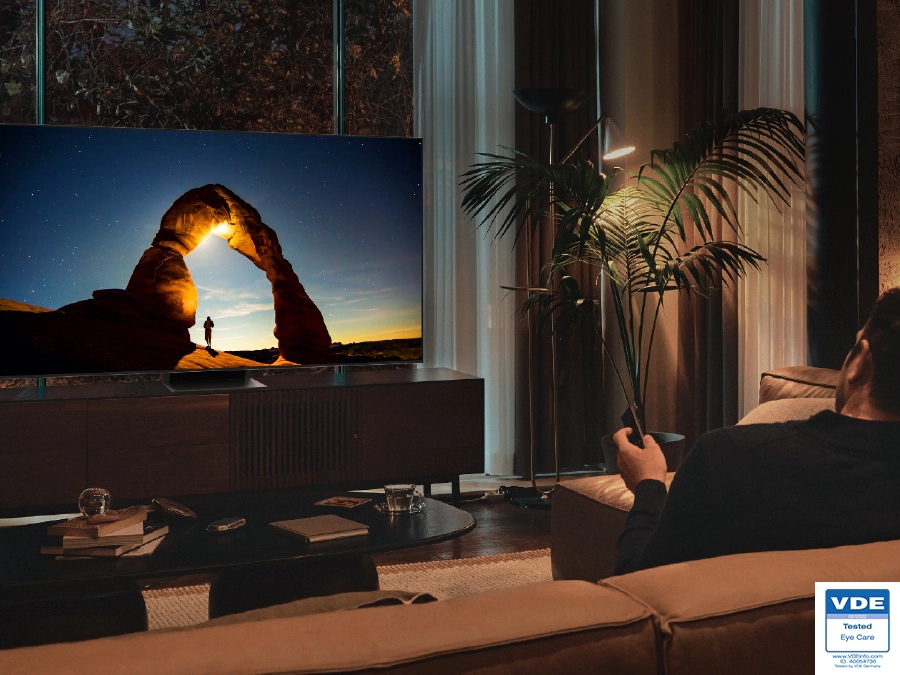رجل يشاهد تلفزيون QLED ليلاً مع ضبط الشاشة على النحو الأمثل في وضع EyeComfort.