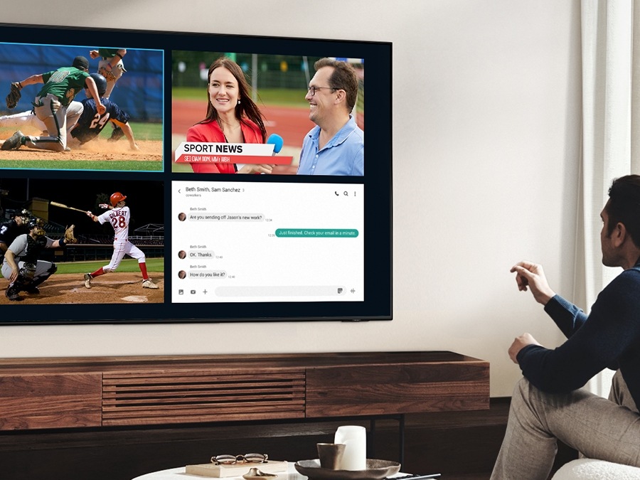 رجل يستخدم ميزة العرض المتعدد QLED للاستمتاع بمباراة كرة القدم وعرض الأخبار على نفس الشاشة في نفس الوقت.