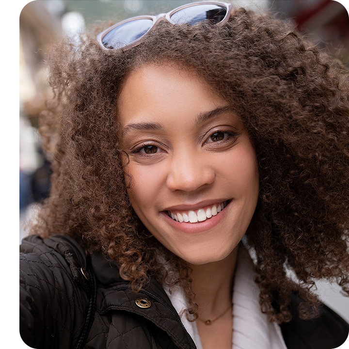 A woman looking into the camera, taking a selfie. The background is subtly blurred out with the bokeh effect.