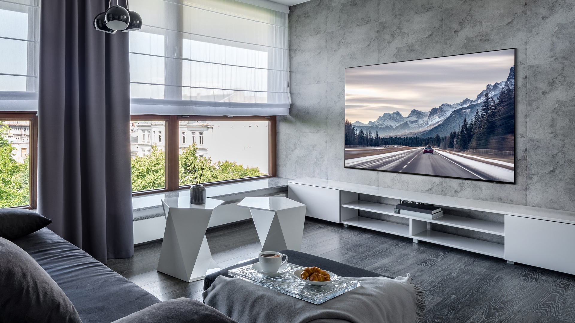 S95D wall-mounted in a modern living room, displaying a scene with mountains.