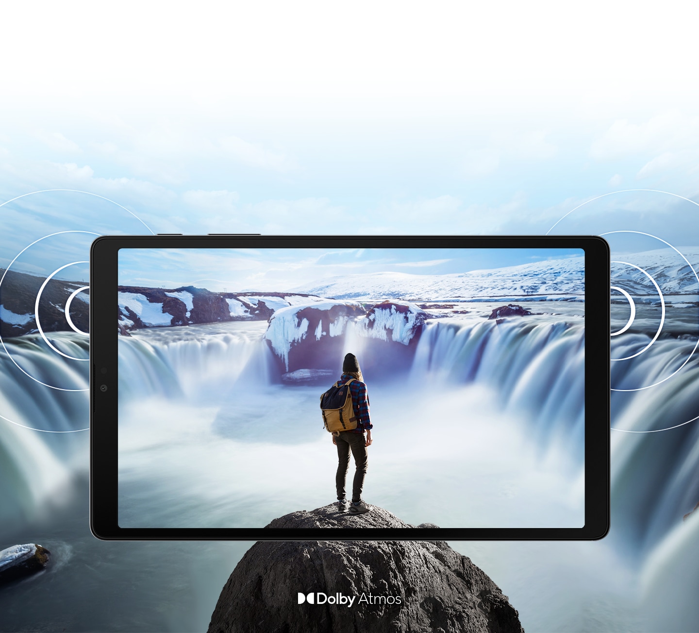 Galaxy A7 Lite seen from the front with an image of a person standing on a rock in front of steaming waterfalls on either side onscreen. The image expands past the edges of the tablet to show the expansiveness of the display. Rings come out from the sides to demonstrate the location of the dual speakers and the immersive sound of Dolby Atmos.