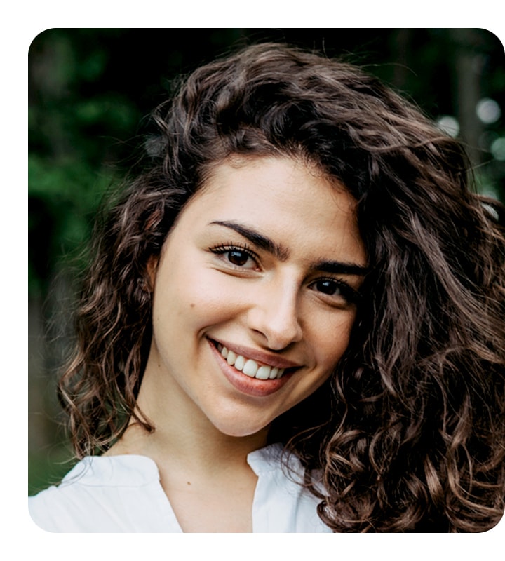 A portrait of a brunette woman shown. She is looking straight at the camera, smiling.