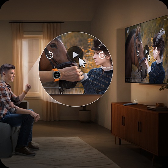 Man wearing a Galaxy Watch watches TV in a living room. He moves his hand back and forth to play the video on the screen.