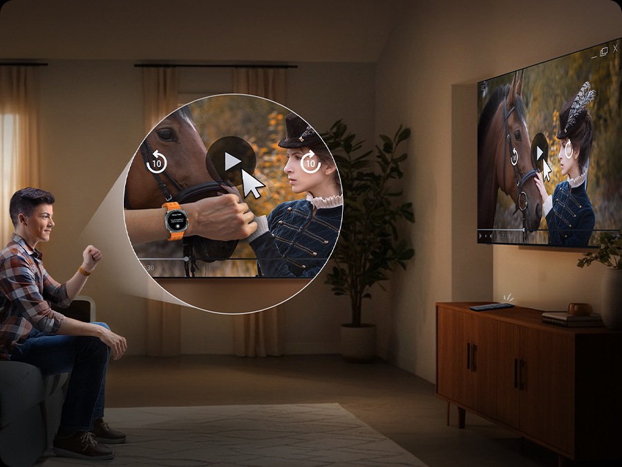 Man wearing a Galaxy Watch watches TV in a living room. He moves his hand back and forth to play the video on the screen.