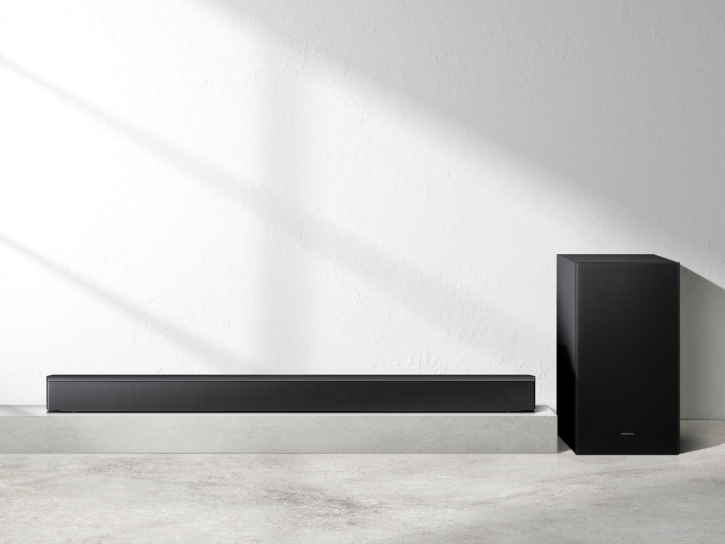 A soundbar and a subwoofer placed on flat surfaces.