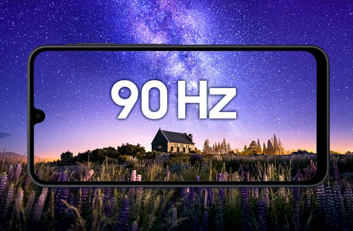 A horizontal view of a black-framed Galaxy A17 smartphone showing a night scene in the background: a stone cottage surrounded by purple flowers under a starry violet-blue sky. '90 Hz' text is centered on the screen, highlighting the display’s smooth motion.