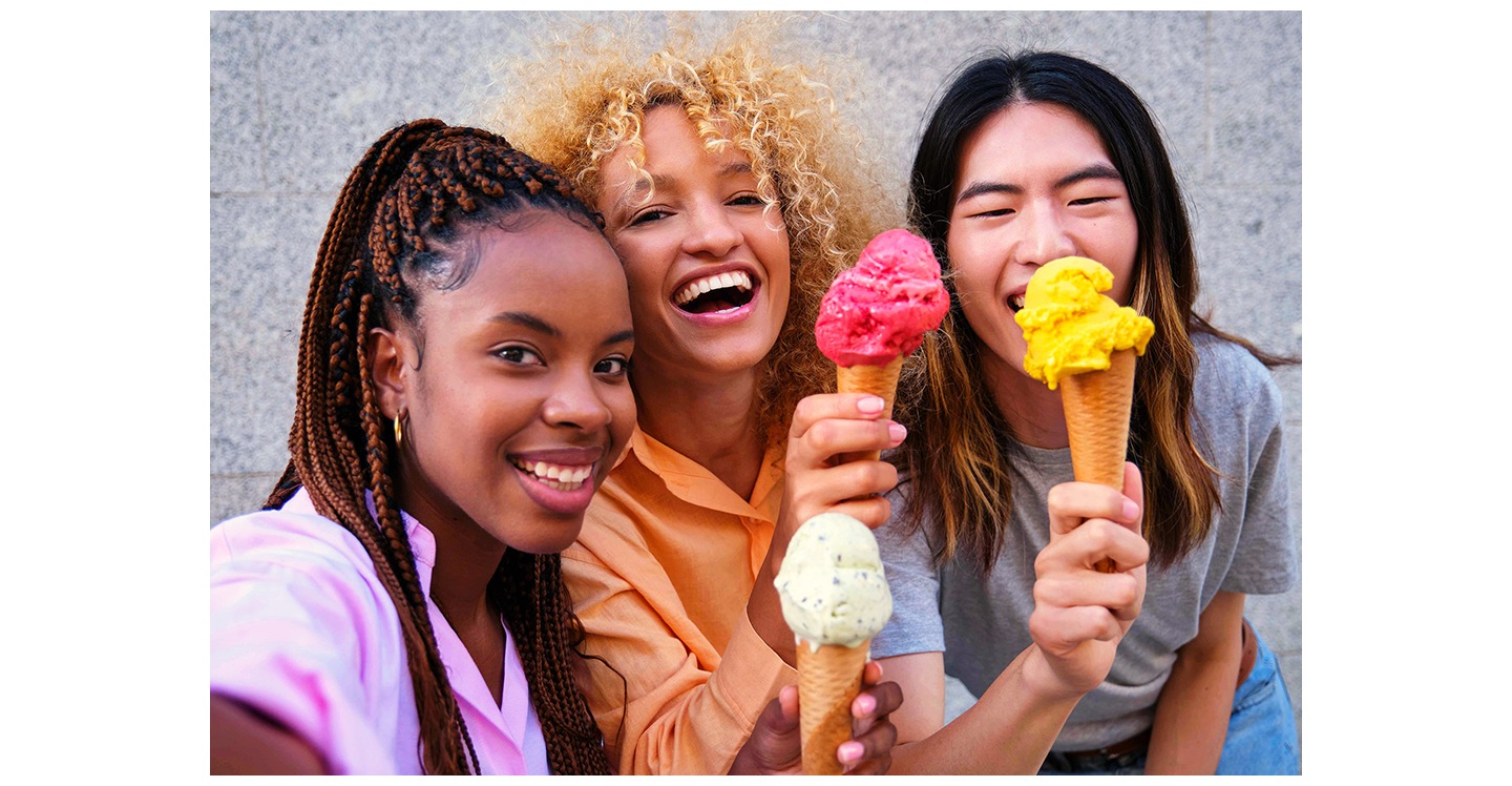 A group of three young people standing close together, smiling and holding ice cream cones while taking a selfie. One of the people is taking the selfie using Galaxy A37 5G's Front Camera for vibrant, sharp photo details.