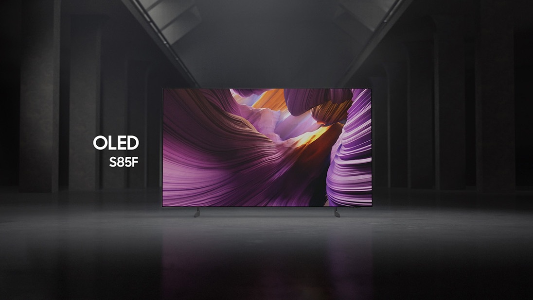 Samsung OLED S85F TV in a black and white indoor space displays a colorful scene of an otherworldly landscape.