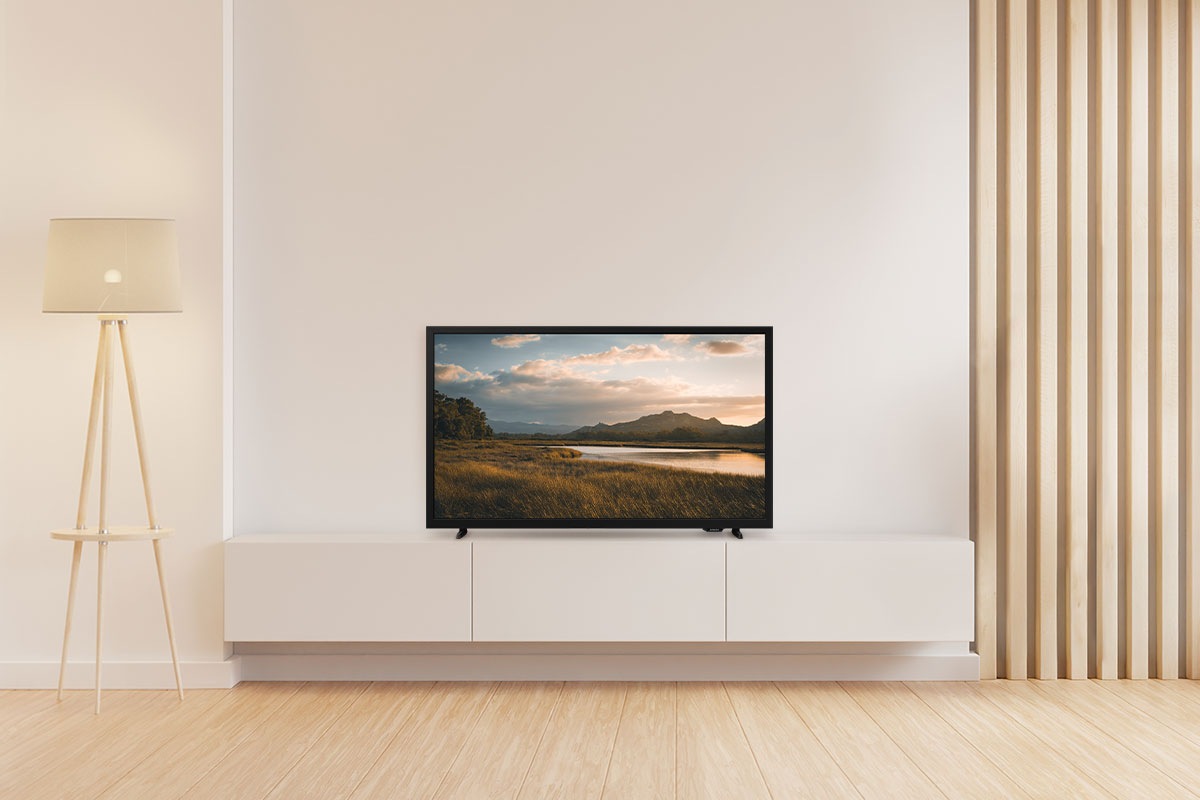 A H5000 is placed on the TV cabinet in a living room. The screen displays a stunning sunset over a serene lake and mountains.