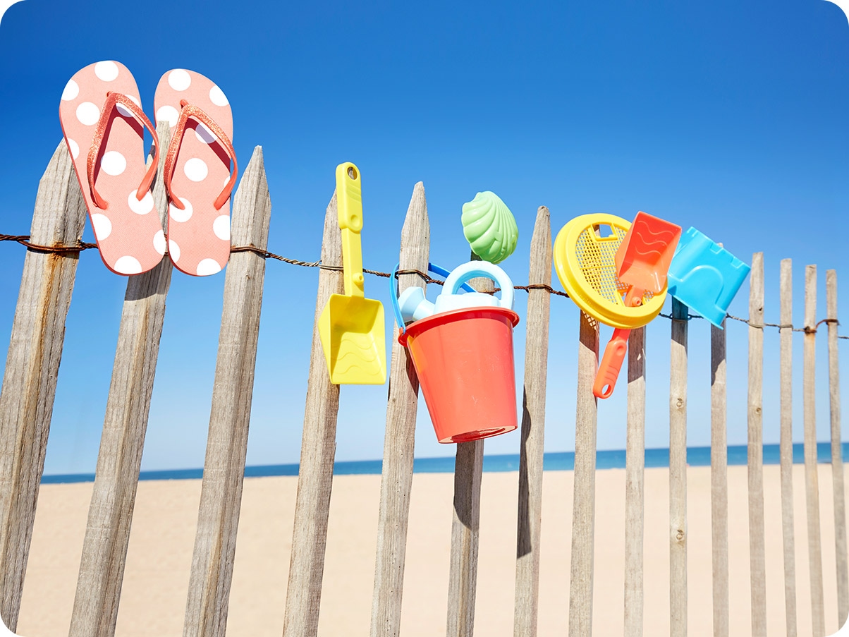 2. Beach toys are drying on a wooden fence. With Ultra Wide Camera, you can see more toys and the beach in the background.