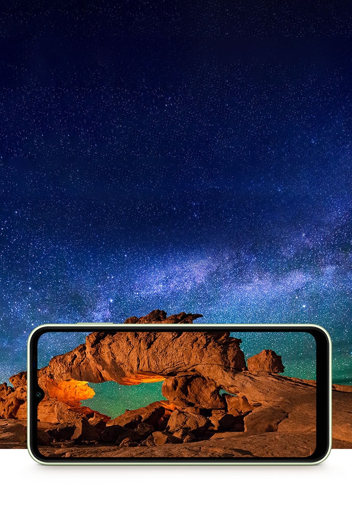 Grandiose orange-brown rocks sit under the vast starlit night sky on Galaxy A14 5G in landscape. The picture extends outside of the device's screen to highlight vivid and immersive experience from the display.