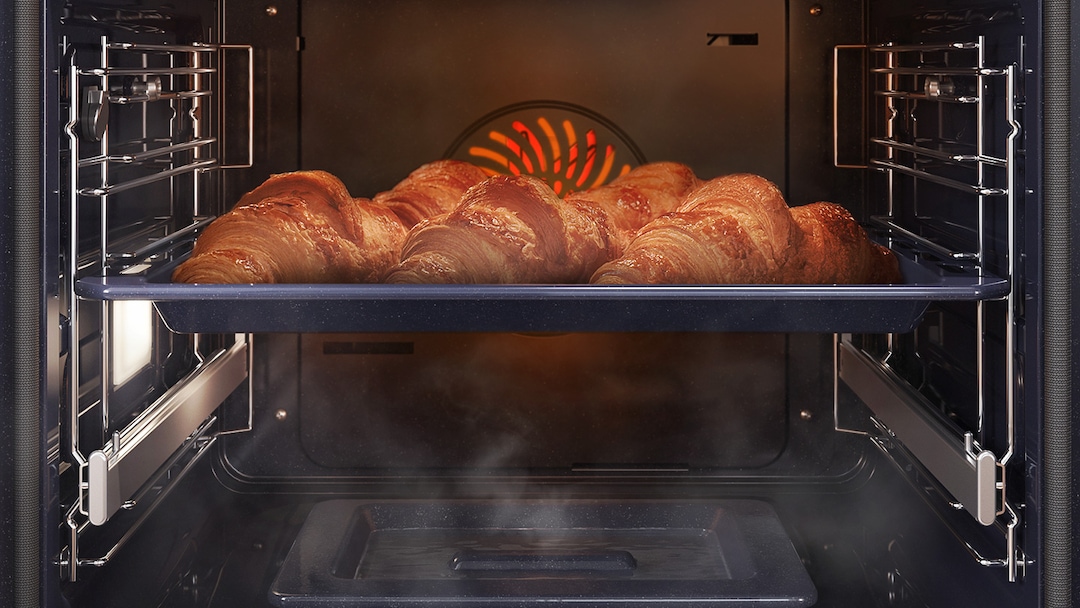 Bandeja de croissants dorándose dentro del horno con vapor