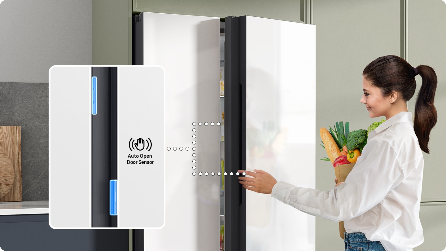 Una mujer con la comida toca el sensor de apertura automática de la puerta para abrir la puerta del refrigerador. Las puertas tienen sensores en ambos lados.