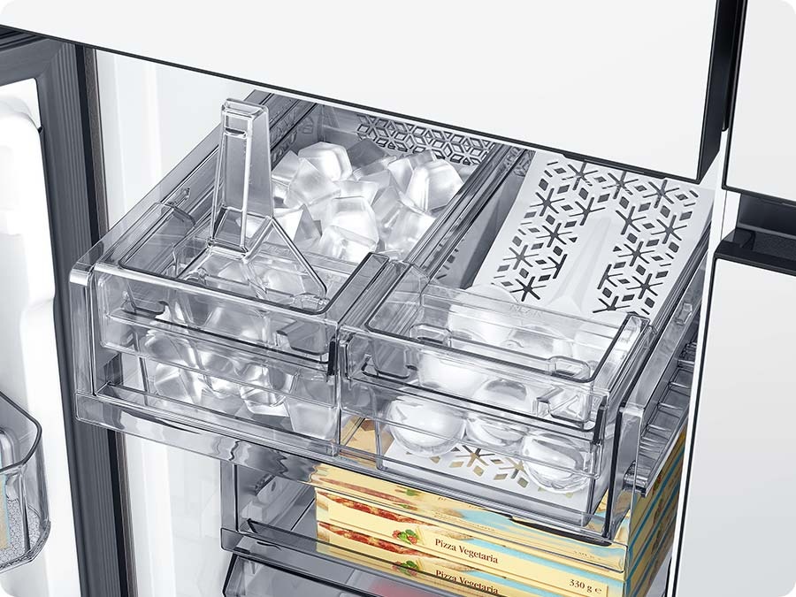 The dual tray in the freezer has ice. The left tray is full of cubed ice and the right tray has whiskey ball ice.
