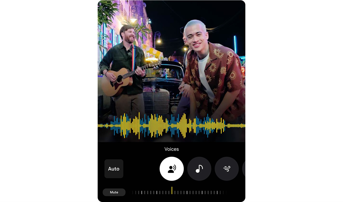 Tres personas están frente a un auto de noche; una toca la guitarra y las otras se inclinan hacia adelante y bailan. El fondo muestra luces de colores y edificios. En la parte inferior aparece una forma de onda de audio, junto con íconos etiquetados como "Automático", "Voces", "Música" y "Ajustes". El ícono Control de ruido es seleccionado. Inicia en cero y disminuye rápidamente hasta -100 para indicar la reducción del ruido de fondo.