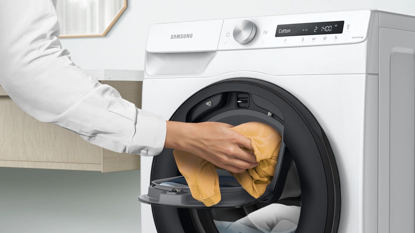 Extra laundry is added into the open AddWash™ door by hand.