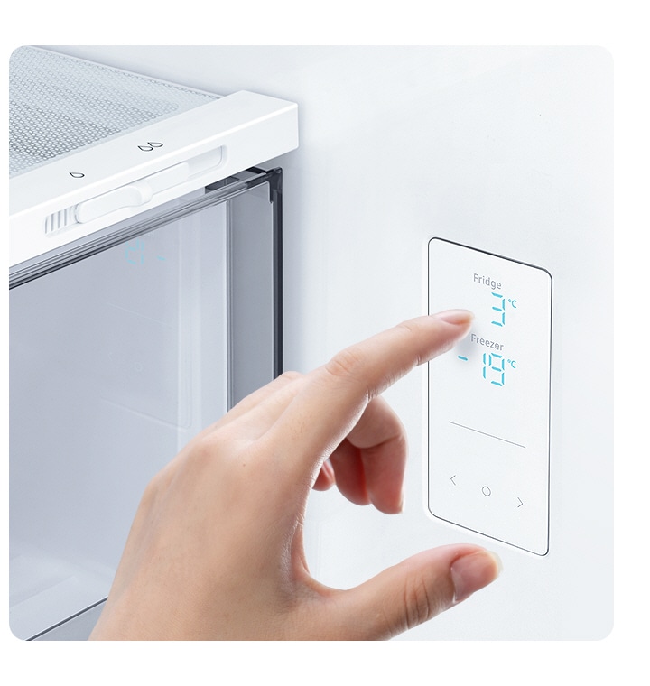 A hand touches the LED screen inside the fridge, with water and ice controls, and temp settings for the fridge and freezer.