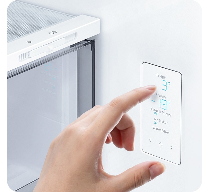 A hand touches the LED screen inside the fridge, with water and ice controls, and temp settings for the fridge and freezer.
