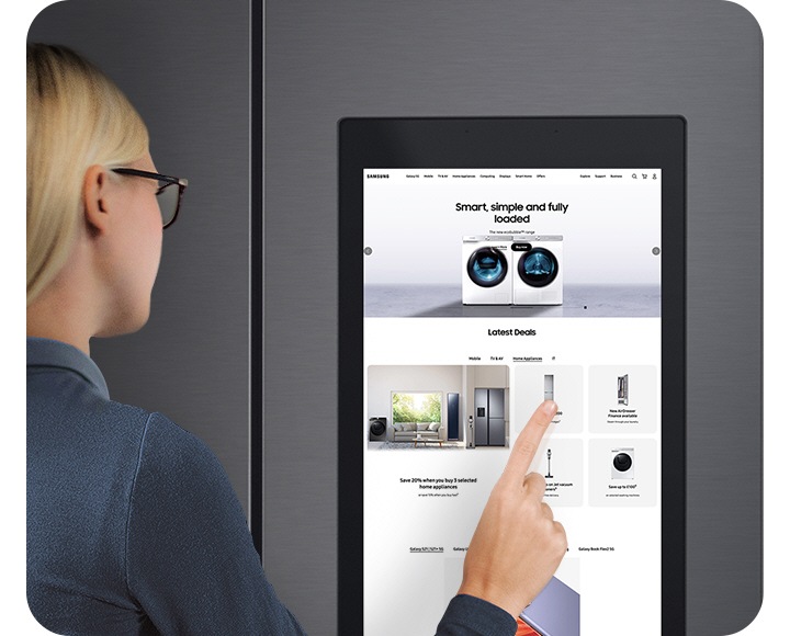 A woman looks at and touches the Family Hub display, navigating through various products being sold on Samsung.com.