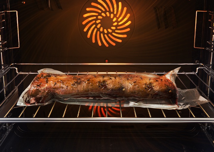 Shows a joint of meat inside the oven, which is tightly sealed in a plastic bag and on a metal tray, being cooked using the Air Sous Vide system.