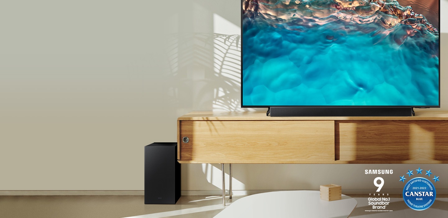 Samsung B series Soundbar and subwoofer are positioned with Crystal UHD TV on living room cabinet.