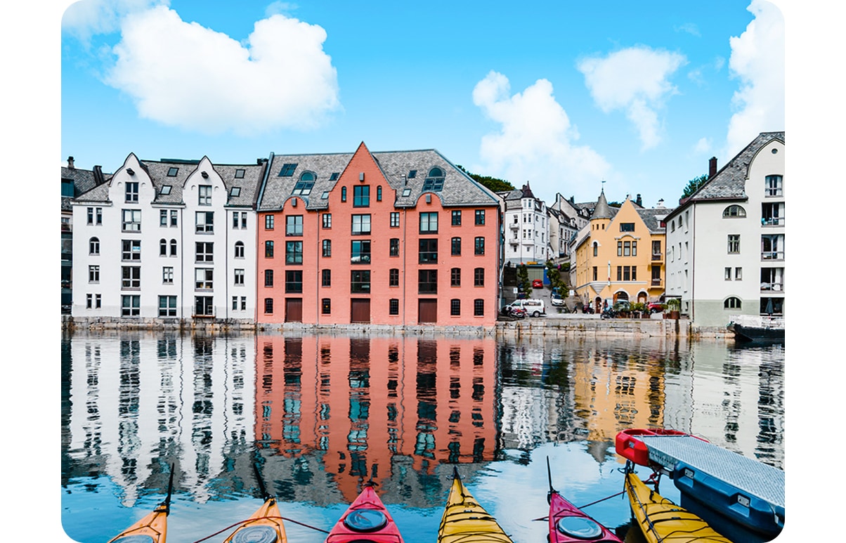 Wide angle icon activated, the shot includes only the tip of the canoes and a portion of the buildings. wide angle are above a landscape of yellow and red canoes lined up in a pier with white and red buildings in the far background.