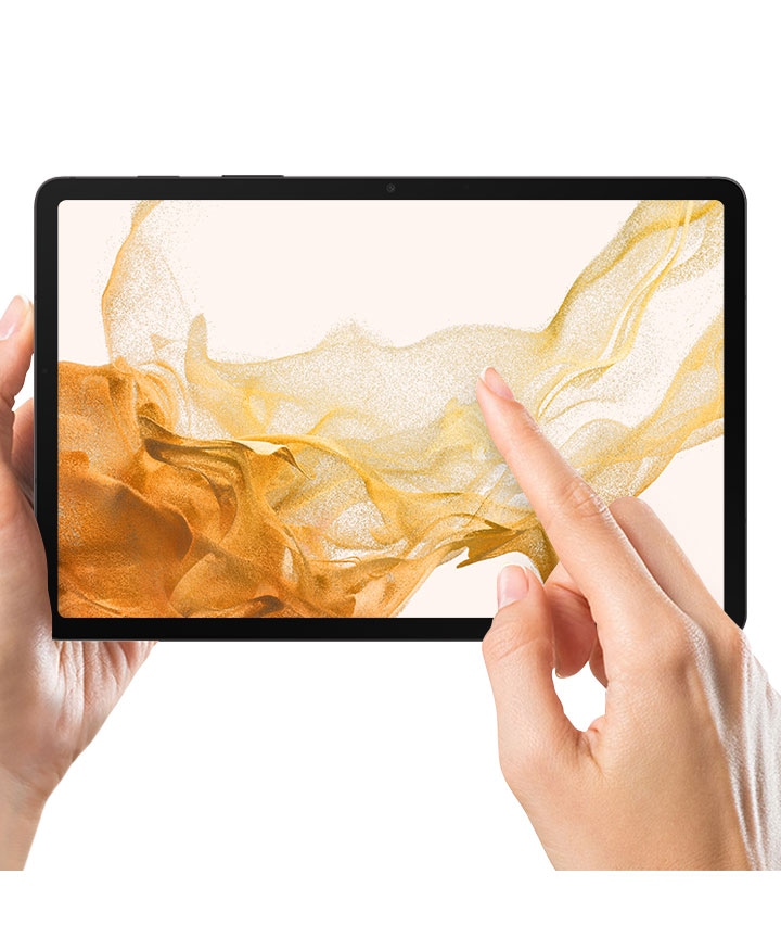 A person holds a Galaxy Tab S8 with the screen protector film on in their left hand. A right index finger touches the screen.