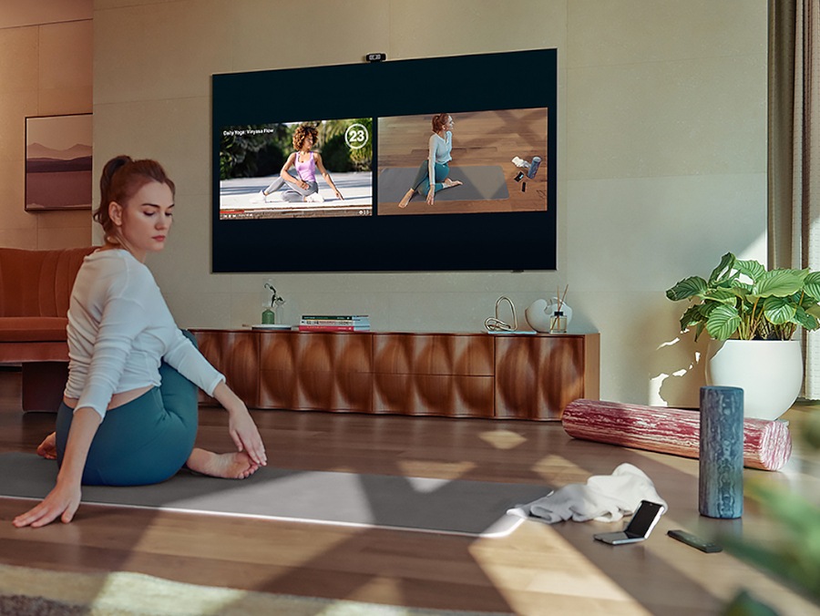 A girl doing yoga stretches and watching the TV screen for instructions