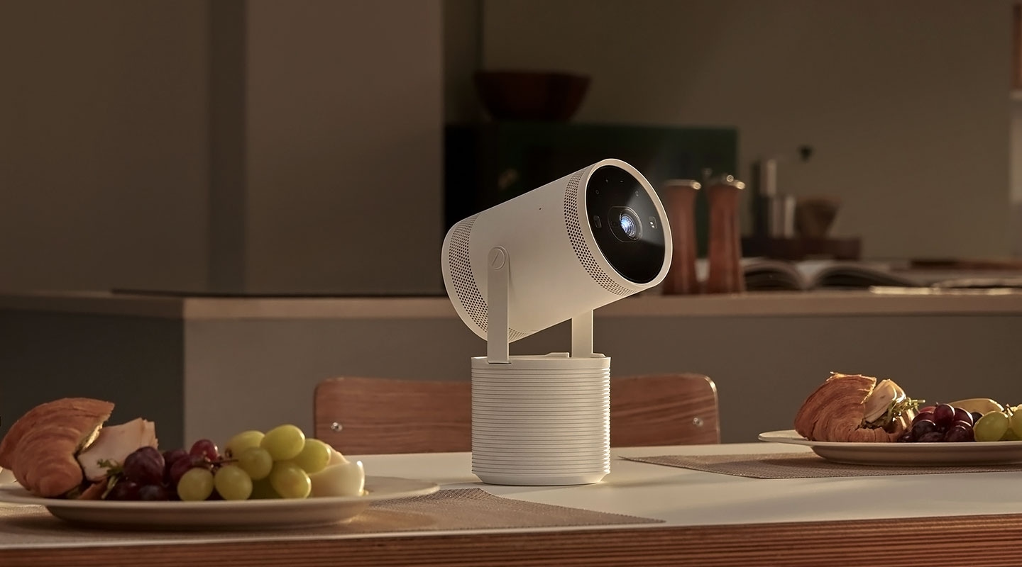 A freestyle projector on a white stand sitting on a kitchen table surrounded by plates of food