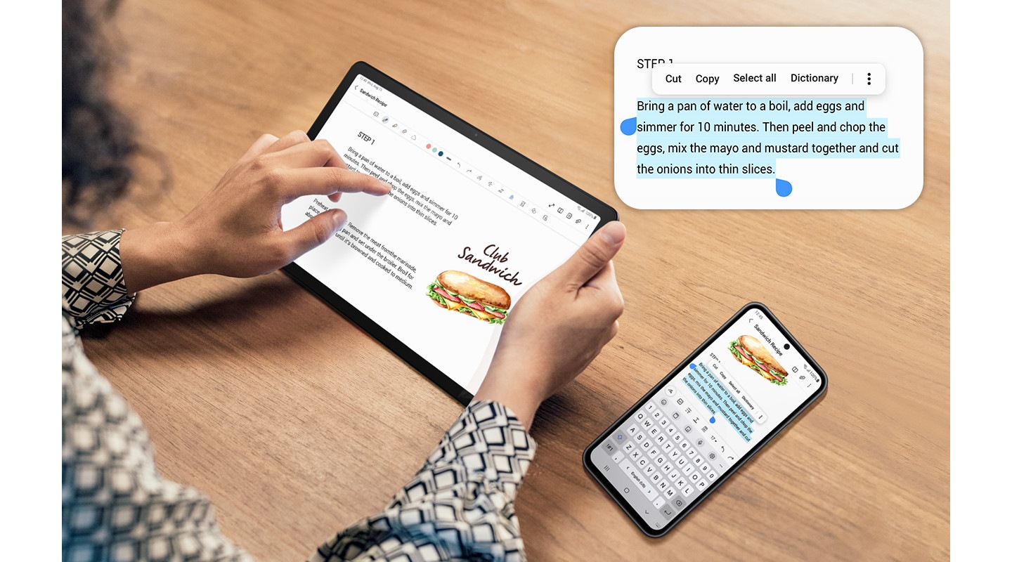 A person is tapping on Galaxy Tab A9+. On the right is a Galaxy smartphone. Both devices are displaying the same screen. The smartphone has a part of the text selected in blue, to indicate the copy and paste feature across devices. Above the devices is the selected part magnified, with options to select all, cut, copy, share and more.