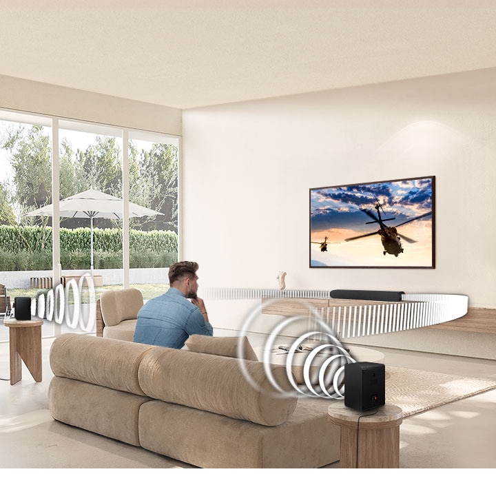 A man watches TV. A Soundbar and rear speakers give off sound waves of various types, traveling in different directions.