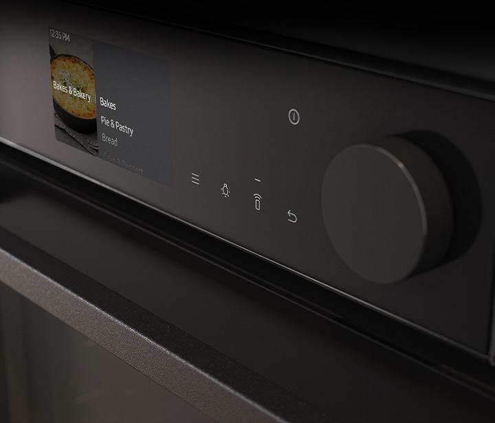 Shows a close-up of the oven's stylishly minimalist control panel with an LCD display, which shows pictures of the various cooking options, touch control and a single knob.
