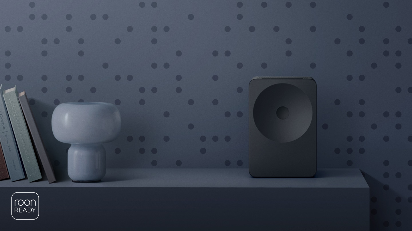A minimalist shelf featuring Music Studio 7 speaker with a sculptural design, styled like an art object. Roon Ready logo.