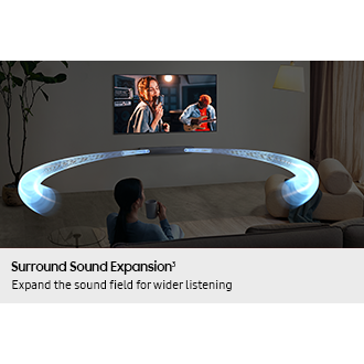 A woman watches TV in a living room. Sound waves shoot out from the soundbar and travel in various directions to surround her.