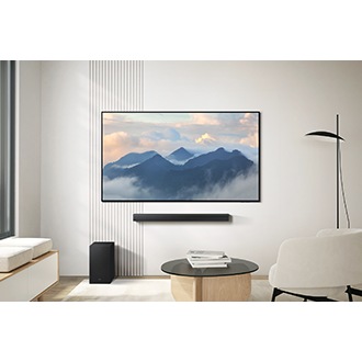 B650F soundbar placed beneath a TV in a living room. A subwoofer is placed on the floor too.