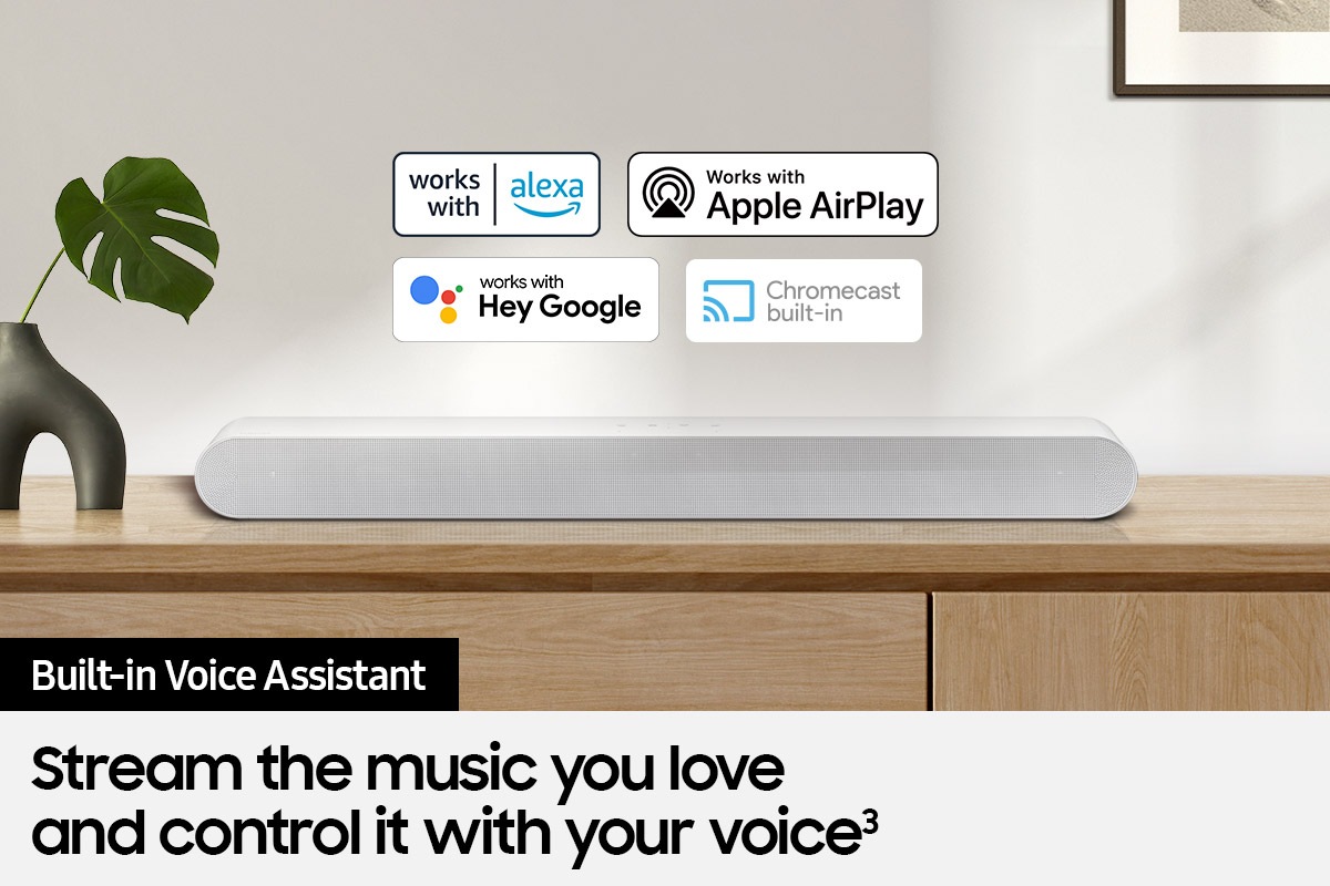 Alexa logo, Apple AirPlay logo, Hey Google logo, and Chromecast Built-in logo can be seen along with Samsung S61B soundbar which is sitting on living room cabinet.